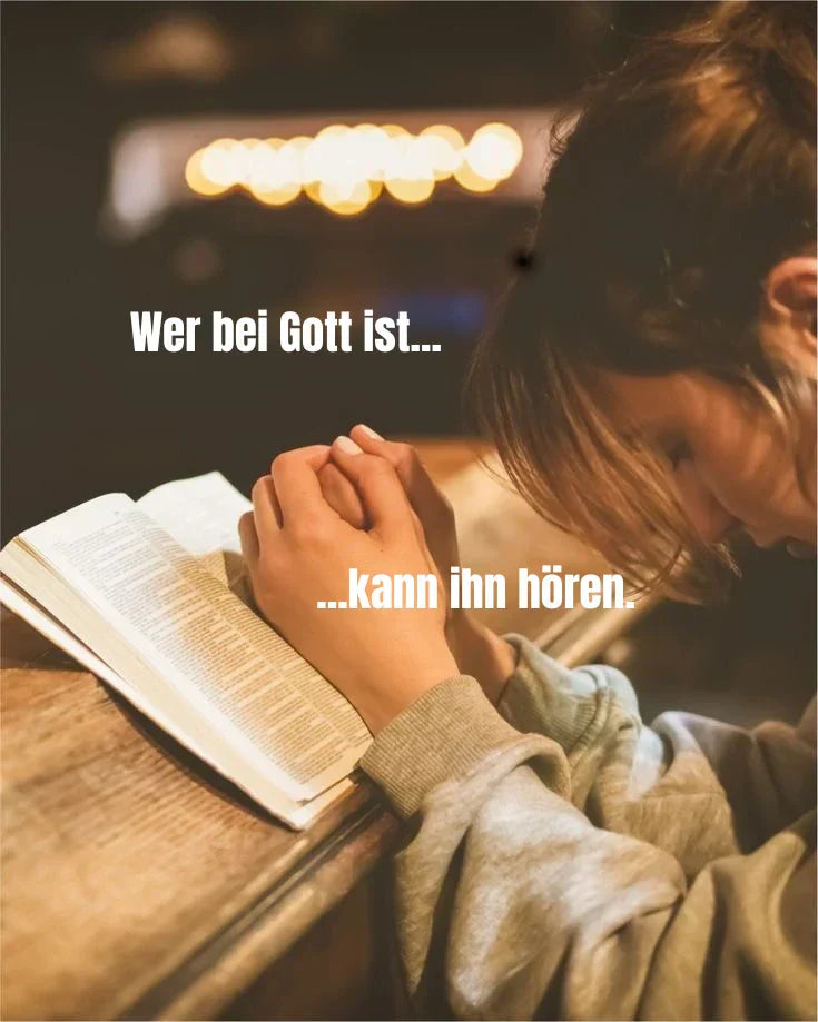Betende Person mit gefalteten Händen über einer offenen Bibel, mit dem Text "Wer bei Gott ist, kann ihn hören" - Symbol für Gebet, Glauben und innere Stille