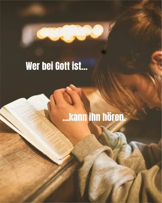 Betende Person mit gefalteten Händen über einer offenen Bibel, mit dem Text "Wer bei Gott ist, kann ihn hören" - Symbol für Gebet, Glauben und innere Stille
